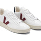 Veja Men's V-12 Leather Sneaker by Veja: Pair of white low-top sneakers with beige soles and maroon "V" logos on the sides. Crafted using recycled materials, the shoes feature white laces, dark blue accents on the heel tabs, and are partly made from organic cotton for added sustainability.