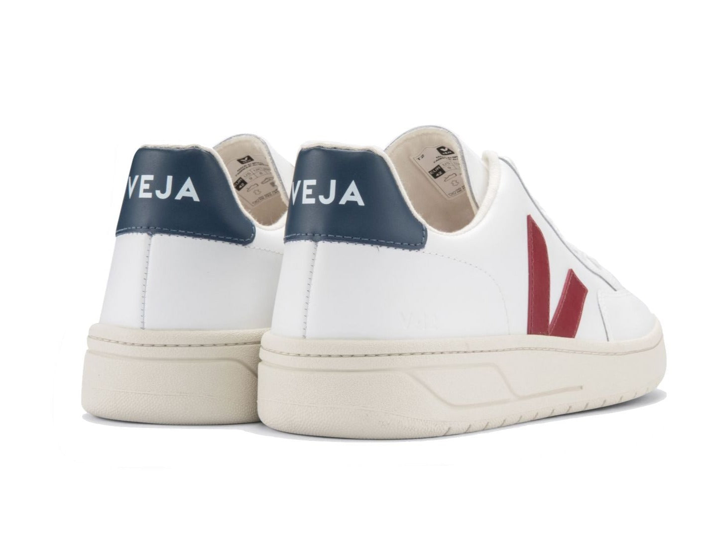 A pair of Veja Men's V-12 Leather Sneakers with navy blue heel tabs and red "V" logos on the sides, crafted from leather and organic cotton, viewed from the back. The sneakers are displayed against a plain white background.