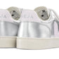 A pair of Veja Junior V-12 Velcro Sneakers in metallic silver with white soles and pink logo detail, made from organic cotton.