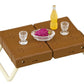 A small brown folding table displays two glasses, a bottle of yellow liquid, a dish of grapes, and Calico Critters Classic Family Car toy accessories arranged neatly on top.