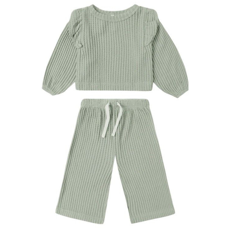 The Quincy Mae Baby Girl’s and Girls’ Ruffle Cozy Set features a light sage green fuzzy waffle knit long sleeve top with ruffles and matching wide-leg drawstring pants.