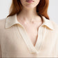A person with long reddish hair wears The Polo by TWP—a cream-colored, ribbed knit short-sleeve sweater featuring a deep V-neck and wide collar.