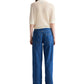 A person stands facing away, wearing TWP's The Polo—a short-sleeve Italian cashmere sweater with a relaxed fit—paired with loose blue jeans, set against a white backdrop.