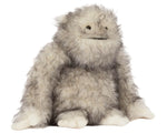 The Bretti Yeti plush toy by Jellycat, featuring a furry gray body, simple smile, and large limbs, sits on a white background evoking the charm of a sacred protector.