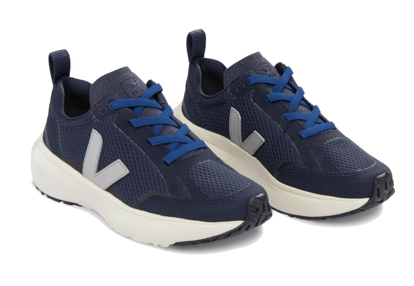 The Veja Junior Canary Alveomesh Sneaker by Veja features a pair of navy blue athletic shoes with white soles and grey "V" logos on the sides. Crafted with recycled polyester, the shoes have blue laces and pull tabs at the heel.