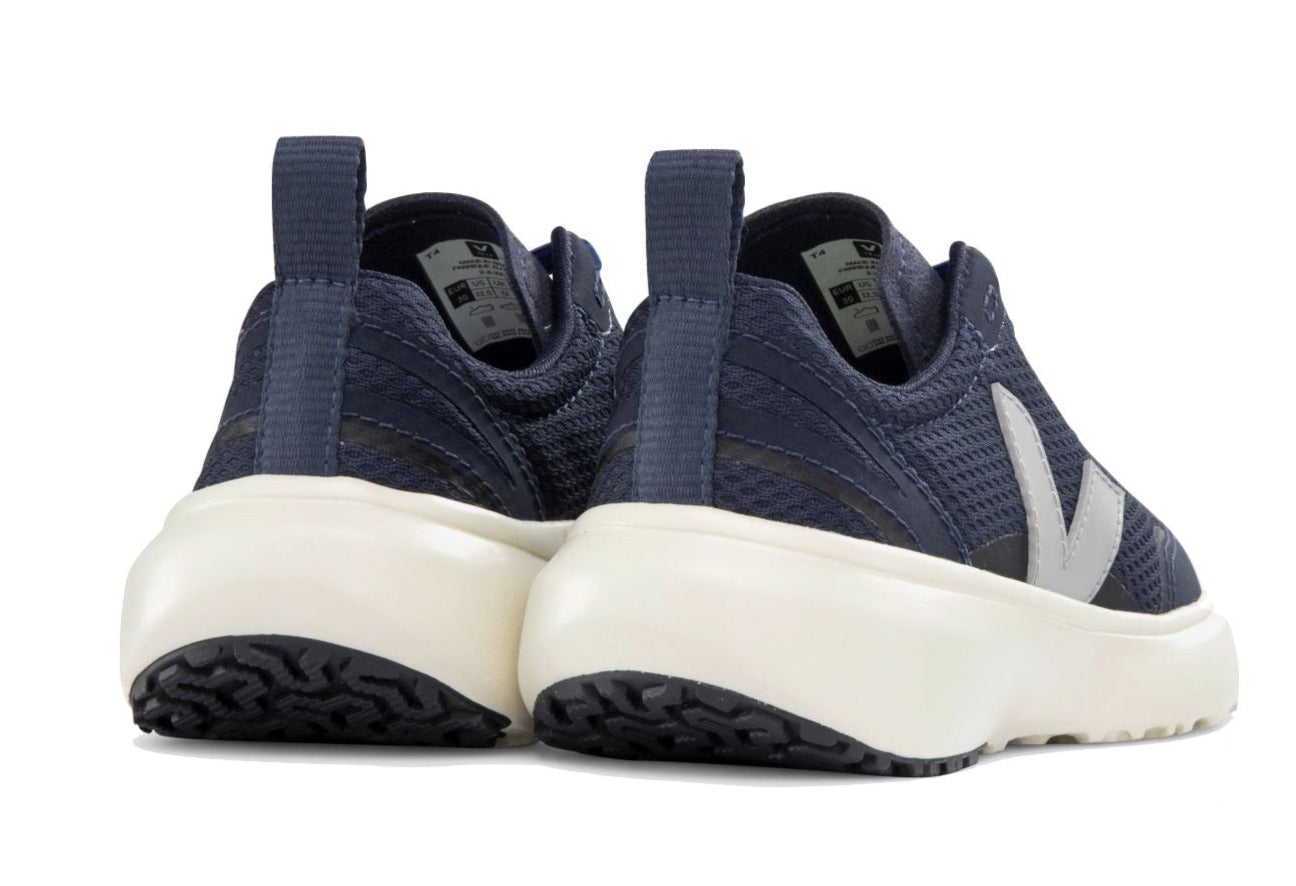 Rear view of a pair of Veja Junior Canary Alveomesh Sneakers by Veja in dark blue, featuring white soles and pull tabs on the heel. The shoes incorporate mesh fabric, branding on the sides, and Amazonian rubber for enhanced sustainability.