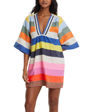 A woman wearing the Lemlem Belkis Caftan, a loose-fitting short dress with wide sleeves and colorful horizontal stripes for a bohemian touch.