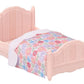 Small pink plastic bed with a floral-patterned blanket and white trim, designed for a dollhouse or toy set—perfectly sized for the Calico Critters Chocolate Rabbit girl from the Red Roof Cozy Cottage collection.
