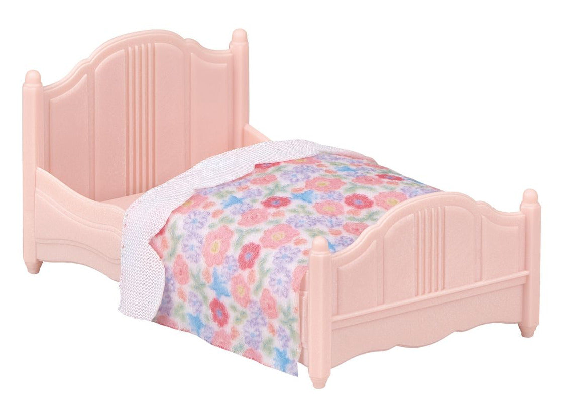 Small pink plastic bed with a floral-patterned blanket and white trim, designed for a dollhouse or toy set—perfectly sized for the Calico Critters Chocolate Rabbit girl from the Red Roof Cozy Cottage collection.