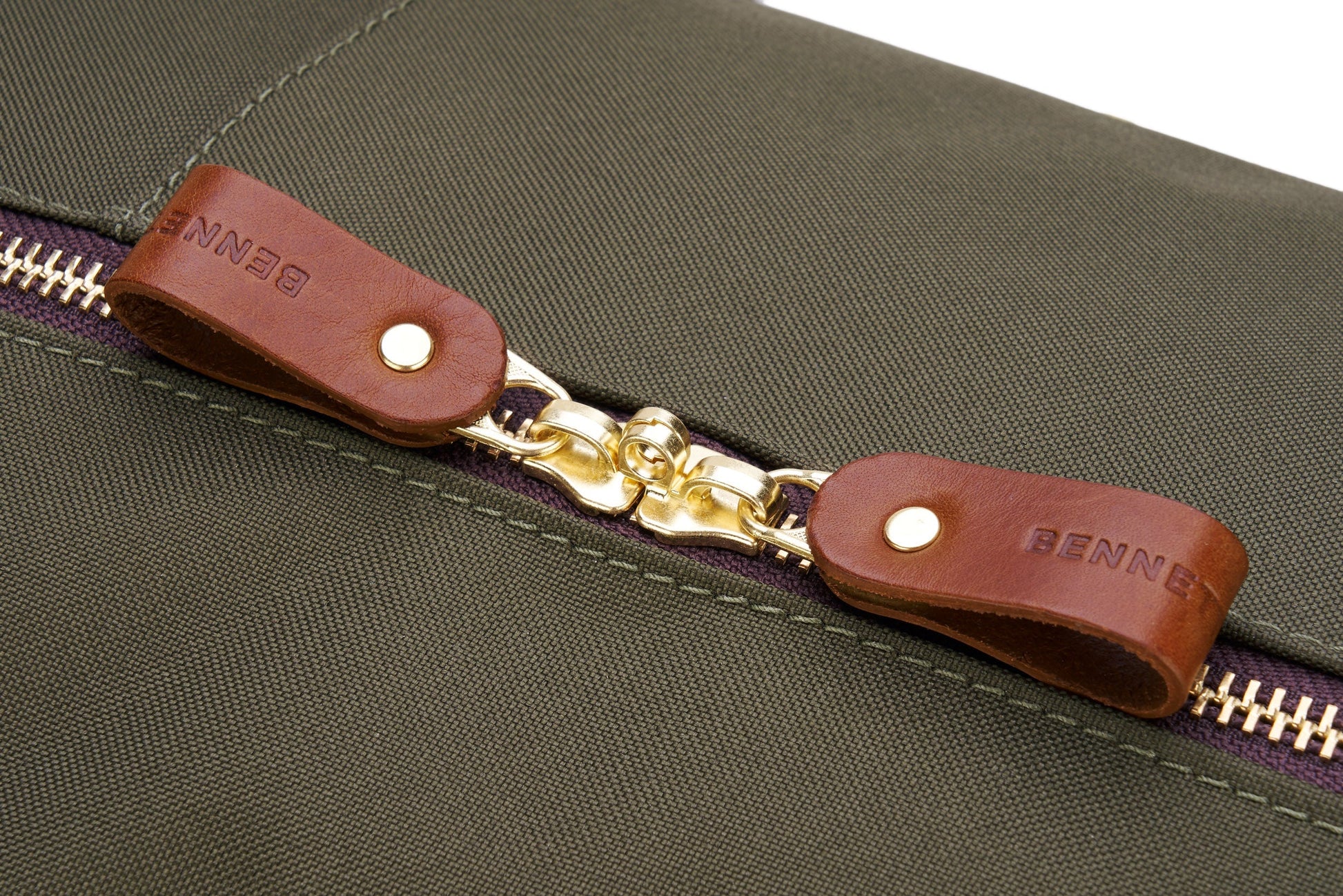 Close-up of the Bennett Winch Medium Cargo, a green heavy-duty kit bag made from waterproof nylon, featuring a gold zipper and brown leather zipper pulls.