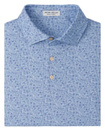 The Parker Performance Jersey Polo by Peter Millar features a light blue tone, subtle floral pattern, four-way stretch, three beige buttons, and inner collar branding. Offers UPF 50+ for stylish comfort and sun protection all day.