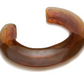 The Ridge Cuff by Lizzie Fortunato is a thin, domed, open-ended resin bracelet in translucent brown with a marbled pattern, curved to fit comfortably around the wrist.