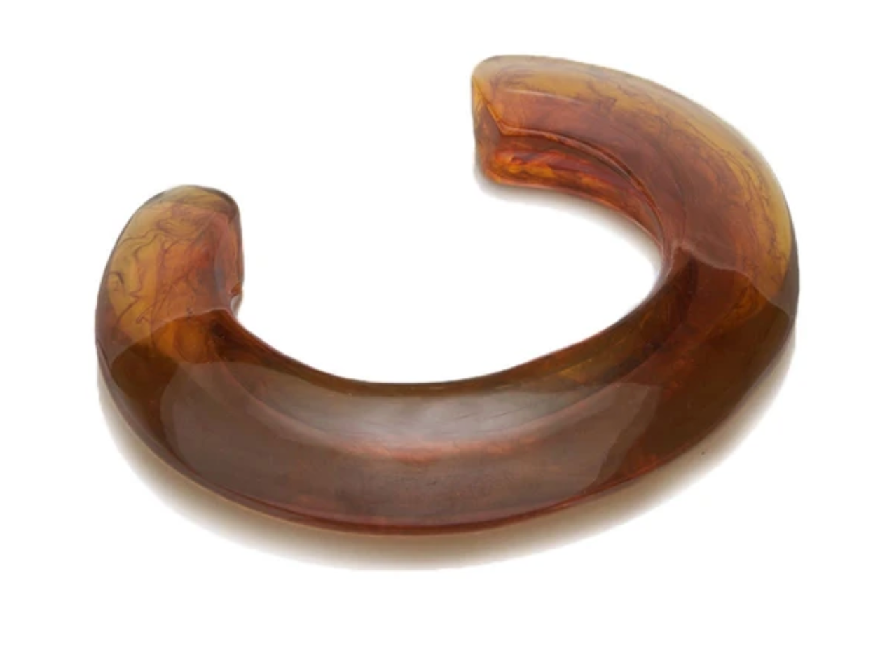 The Ridge Cuff by Lizzie Fortunato is a thin, domed, open-ended resin bracelet in translucent brown with a marbled pattern, curved to fit comfortably around the wrist.