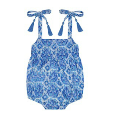 The Mer St Barth Zoe Romper by Mer is a summer essential, featuring a blue and white paisley pattern with playful shoulder ties and tassel detailing, perfect for sunny days.