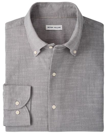 A folded light gray “Devonport Chambray Cotton-Stretch Sport Shirt” by Peter Millar, featuring a visible brand label inside the collar—ideal for elevating your casual style.