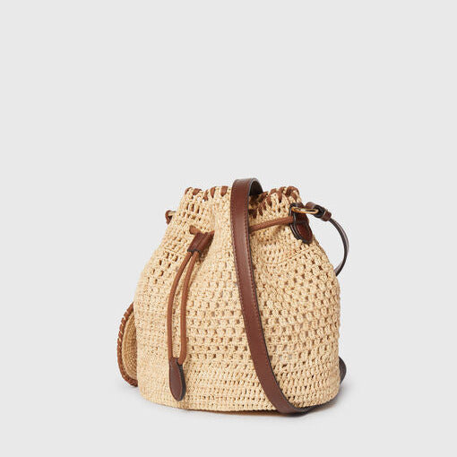 The Stella McCartney Falabella Crochet Raffia Bucket Bag features woven straw with brown leather accents and a drawstring closure, exuding effortless elegance against a plain light background.