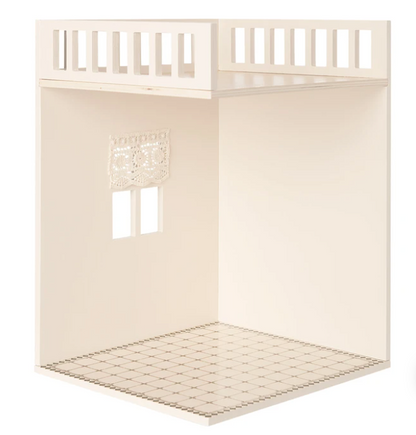 The Maileg House of Miniature Bathroom features a tiled floor, small window with lace curtain, and partial upper railing—an ideal setting for displaying Maileg furniture or designing your own tiny bathroom scene.