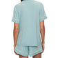 Wearing the Eberjey Gisele Relaxed Short PJ Set in light blue with white trim, a person enjoys a comfortable fit with a short-sleeved top and shorts. A functional pocket elegantly enhances the design as they face away.