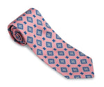 The R. Hanauer Adams Medallion Necktie by R. Hanauer, a 3 1/4 inch silk necktie featuring a blue and white geometric pattern, rolled up for display. Made in the USA.