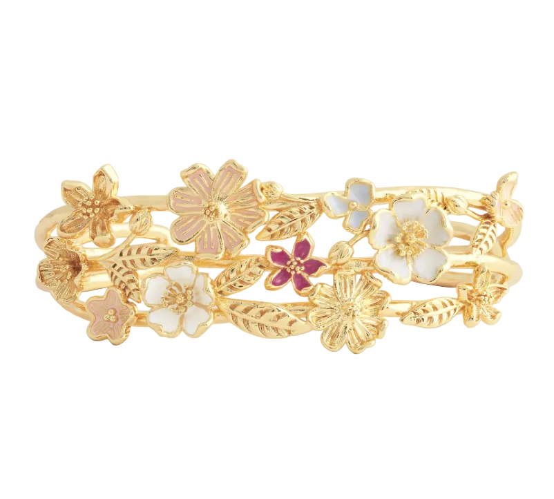 The Anabel Aram Wildflowers Bangle is a gold-plated brass bracelet adorned with hand-painted white, pink, and purple enamel floral and leaf designs.