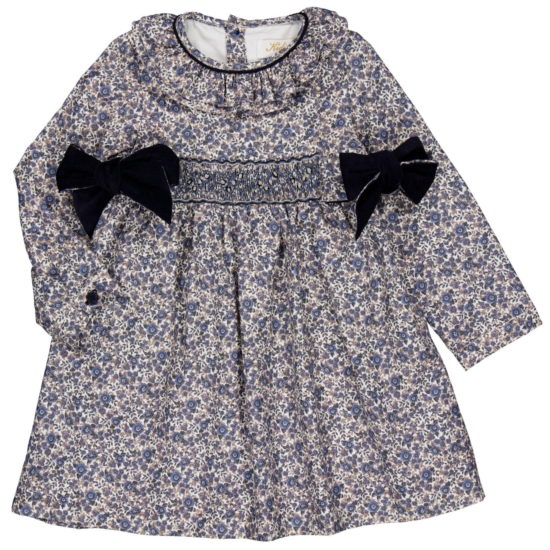 The Kidiwi Baby Girls' and Girls' Adriana Corduroy Bows Smocked Dress features a blue and white floral pattern, handmade smocking on the chest, and two black velvet bows at the waist for a charming look.