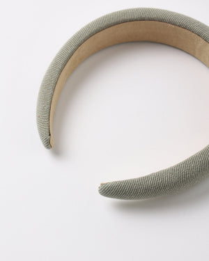 A close-up of the Rylee & Cru Girls’ Padded Headband, featuring a stylish, fabric-covered design in a light grayish-green color, displayed against a white background.