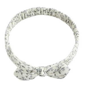 The Rylee & Cru Baby Bow Headband features a soft white band with a gray leaf pattern, a small bow, and a comfy scrunchy elastic back for babies.