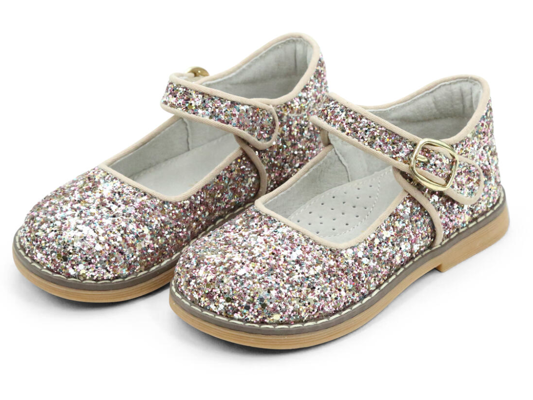 The L'Amour Natasha Glitter Mary Jane by L'Amour Shoes, featuring sparkly pink and silver glitter and ankle straps with buckles, are the perfect finishing touch for any outfit, adding an extra dose of sparkle to your child's step.