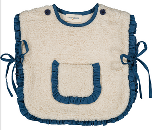 The LL Capuchon Fake Fur Poncho by Louis Louise features a cream sherpa design, blue ruffled edges, blue side ties, a center pocket, and button fastenings at the shoulders.