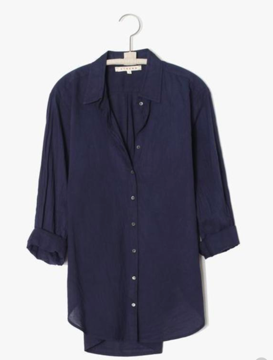 The Xirena Beau Shirt, a navy blue cotton poplin button-up with long sleeves and a collar, is displayed on a hanger against a plain white background.