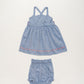 The Early Sunday Baby Girls’ Alice Baby Dress & Bloomer Set features a sleeveless blue cotton chambray dress with crisscross straps and adorable pink heart accents, paired with coordinating blue bloomers—evoking the charm of a summer sky, all showcased on a simple white background.