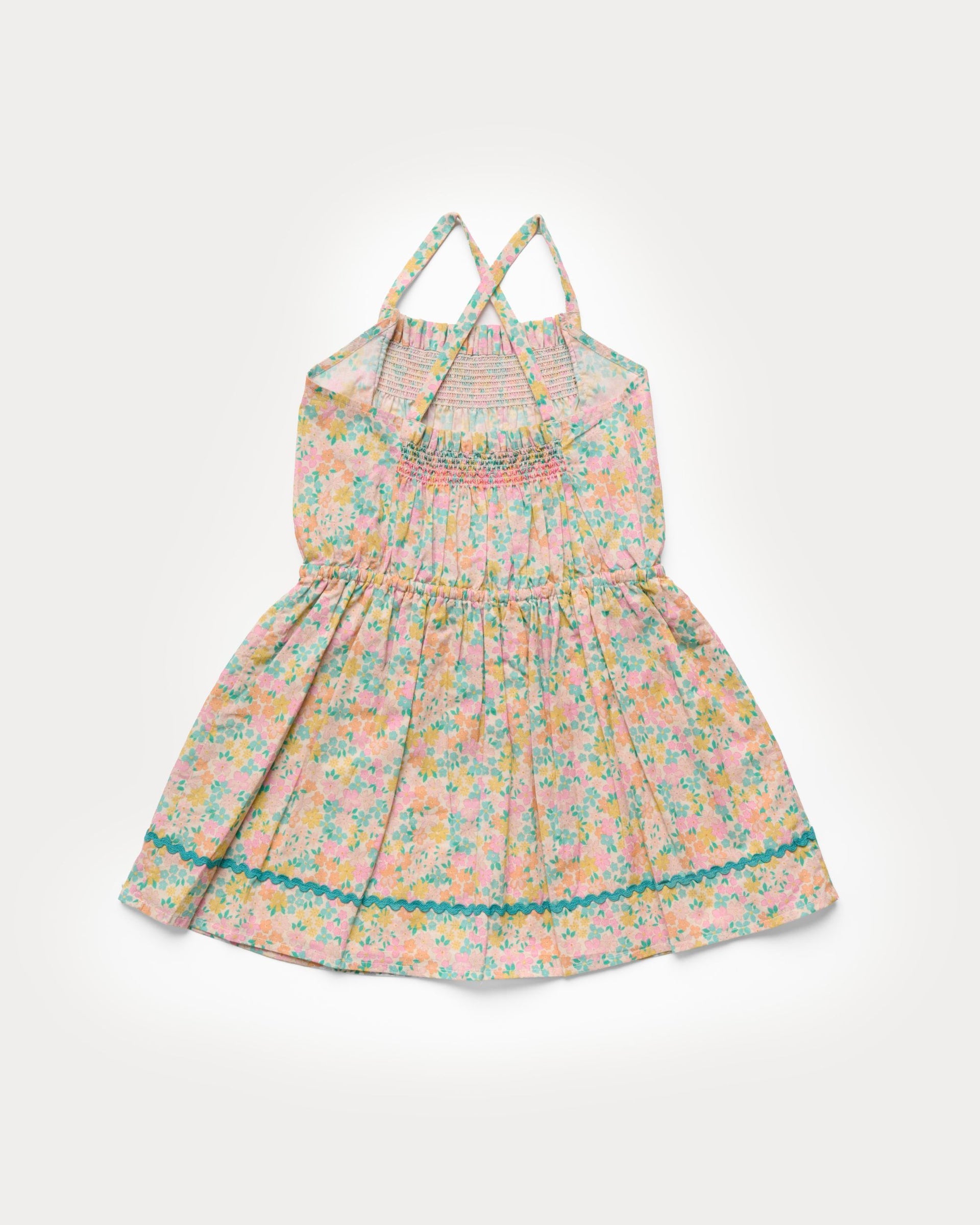 The Girls’ Alisson Dress by Early Sunday is a light pink sleeveless summer dress for children, featuring delicate floral patterns, smocking on the bodice, crisscross straps, and a flared skirt—crafted from soft organic cotton to ensure all-season comfort.