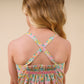 A young girl with light brown hair is shown from the back, wearing the Early Sunday Girls’ Alisson Dress, a floral mint dress featuring crisscross straps and gathered elastic at the top.