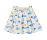 The Girls' Aloe Skirt by Arsene & Les Pipelettes is crafted from organic cotton in a breathable double voile for all-day comfort, featuring a gold elasticated waistband and decorated with blue wave and leaf patterns accented by orange circles, shown against a plain background.