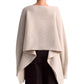 A person wearing the Altuzarra Trip Sweater, an oversized beige cashmere knit with a draped back, over black pants.