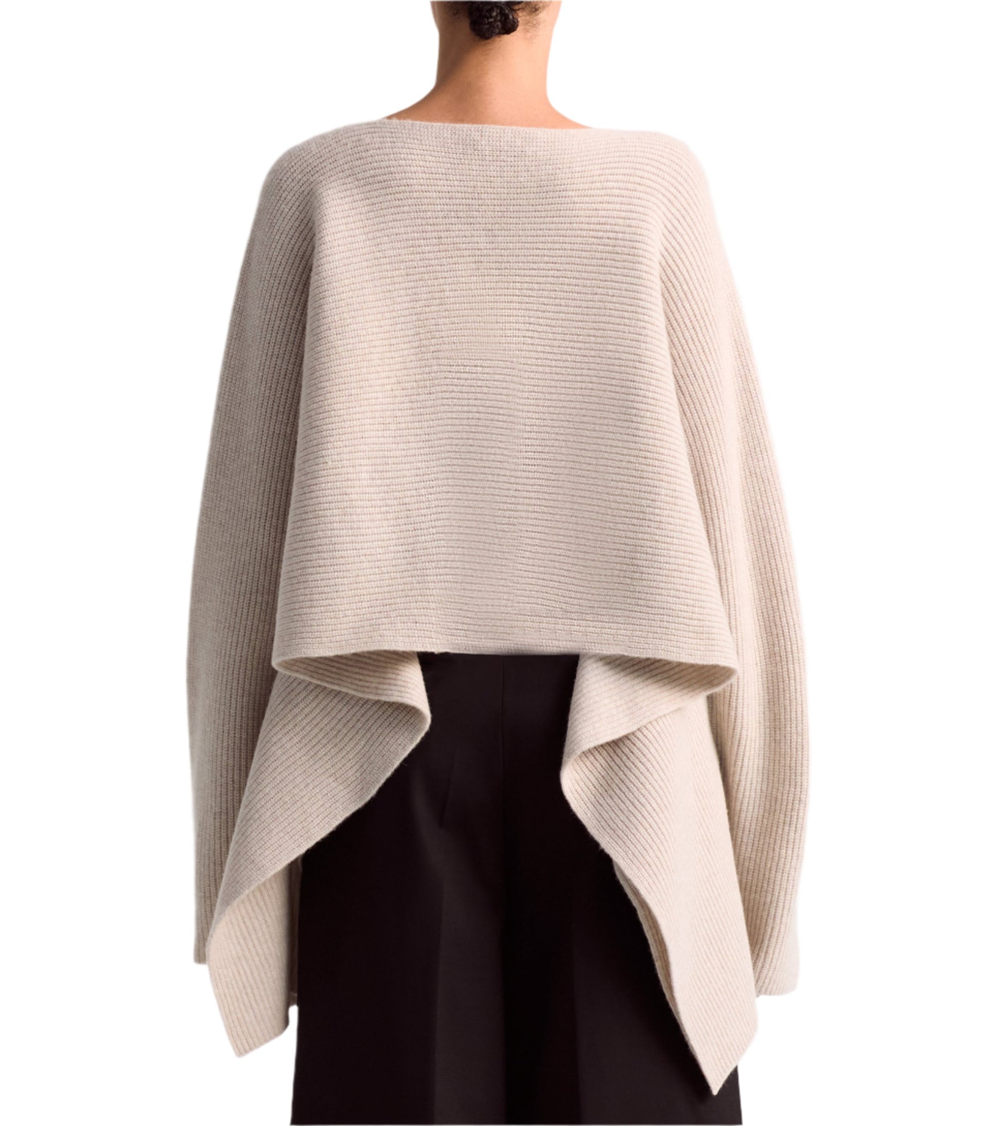 A person wearing the Altuzarra Trip Sweater, an oversized beige cashmere knit with a draped back, over black pants.