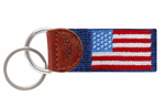 The Smathers & Branson American Flag Key Fob, Navy, features a fabric tag with an American flag pattern. It is attached to two metal key rings and a leather tab embossed with the initials "S&B." This needlepoint key fob adds a colorful personality to your pocket or purse.