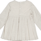 The Girls' Ashley Organic Cotton Twill Dress by Kidiwi is a cream-colored, long-sleeve children's dress with pleats and back buttons, shown from the back.