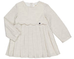 The Kidiwi Girls' Ashley Organic Cotton Twill Dress is a cream long-sleeve style for young children, featuring a pleated skirt, scalloped bodice detail, and a decorative button.