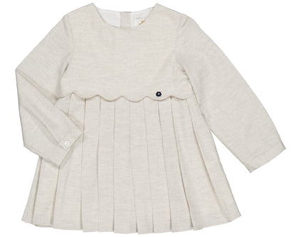 The Kidiwi Girls' Ashley Organic Cotton Twill Dress is a cream long-sleeve style for young children, featuring a pleated skirt, scalloped bodice detail, and a decorative button.