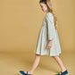 A young girl with long blond hair, wearing the Kidiwi Girls' Rison Smocked Dress with Olive Velvet Collar, walks against a plain beige background.