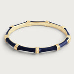 Anabel Aram Bamboo Hinged Bangle, sculpted in gold and dark blue with “ANABEL ARAM” engraved inside, features a hidden clasp and is shown on a plain light background.