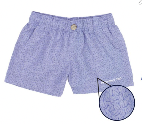 The Boys' Mallard Short by Properly Tied features a light purple color, elastic waistband, front pockets, button closure, moisture-wicking fabric, and a subtle geometric pattern shown in a magnified inset.