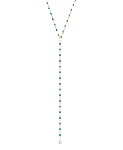 Introducing the Gigi Clozeau Party Y Necklace 19.7", a stunning piece showcasing a gold lariat design embellished with green beads and an eye-catching round pendant, enhanced by elegant resin pearls from the renowned brand Gigi Clozeau.