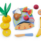 The Tenderleaf Tropical Fruit Chopping Board from Tender Leaf Toys includes a colorful arrangement of wooden toy fruits such as a pineapple, coconut, watermelon, dragon fruit, passion fruit, and banana. This delightful toddler kitchen toy features a blue face-shaped mat with a small knife and also comes with a wooden cutting board for endless imaginative play.