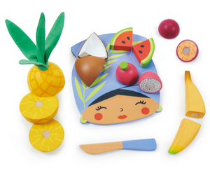 The Tenderleaf Tropical Fruit Chopping Board from Tender Leaf Toys includes a colorful arrangement of wooden toy fruits such as a pineapple, coconut, watermelon, dragon fruit, passion fruit, and banana. This delightful toddler kitchen toy features a blue face-shaped mat with a small knife and also comes with a wooden cutting board for endless imaginative play.