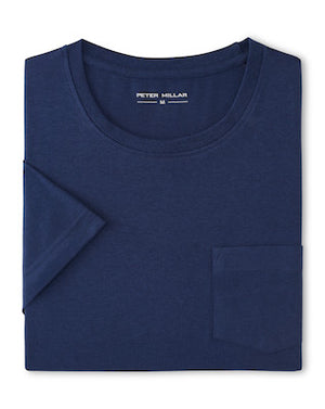 A folded navy blue Crown Comfort Short-Sleeve Pocket Tee by Peter Millar is displayed, crafted from soft midweight organic cotton with a chest pocket and a visible "Peter Millar" label inside the collar. This tee combines everyday comfort and style.