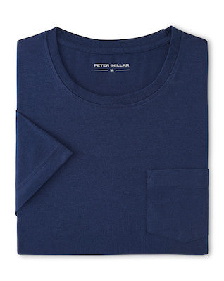 A folded navy blue Crown Comfort Short-Sleeve Pocket Tee by Peter Millar is displayed, crafted from soft midweight organic cotton with a chest pocket and a visible "Peter Millar" label inside the collar. This tee combines everyday comfort and style.