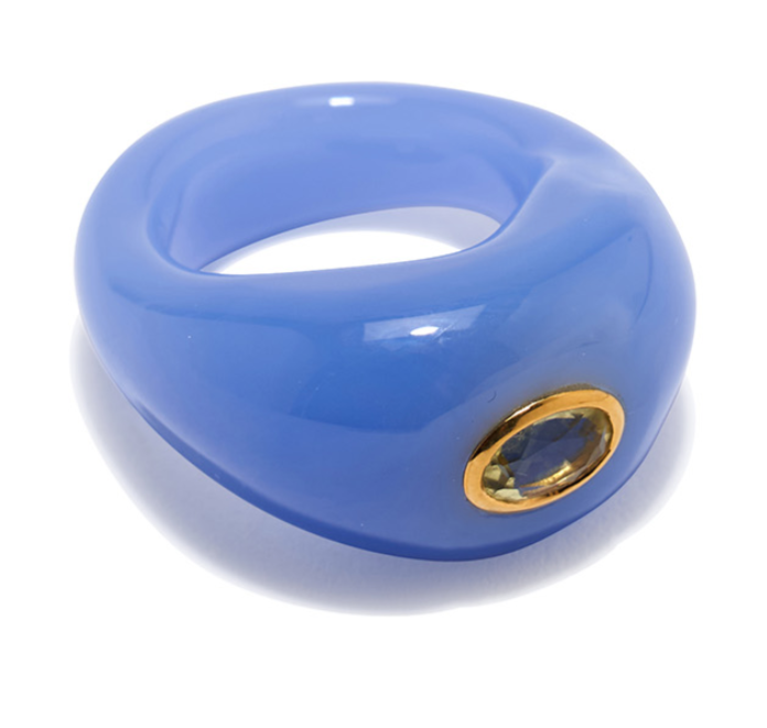 The Monument Ring by Lizzie Fortunato features a chunky, glossy blue band with a gold-rimmed oval gemstone set to one side, making this artistic cocktail ring a true statement piece.
