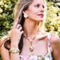 Woman wearing the Juliska Capucine De Wulf Villandry Fleur Vine Ring in Mother of Pearl, standing outdoors with greenery in the background.